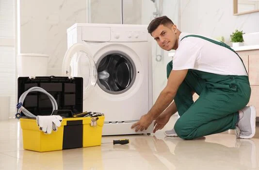 Service professional working beside a front-loading washing machine
