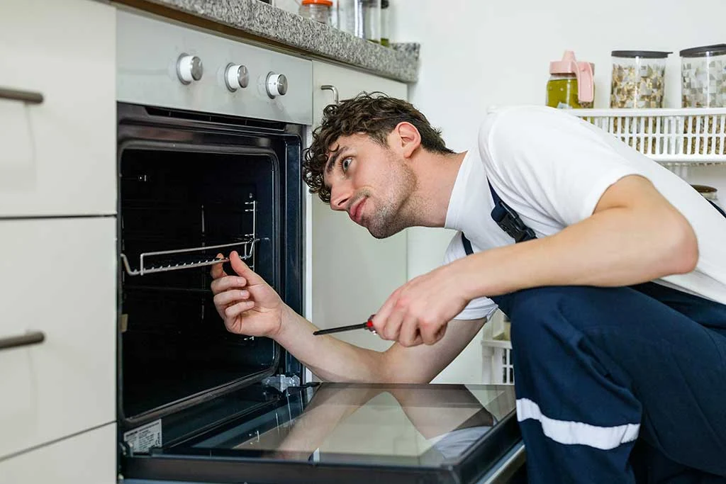 Technician checking the inside of an open kitchen oven